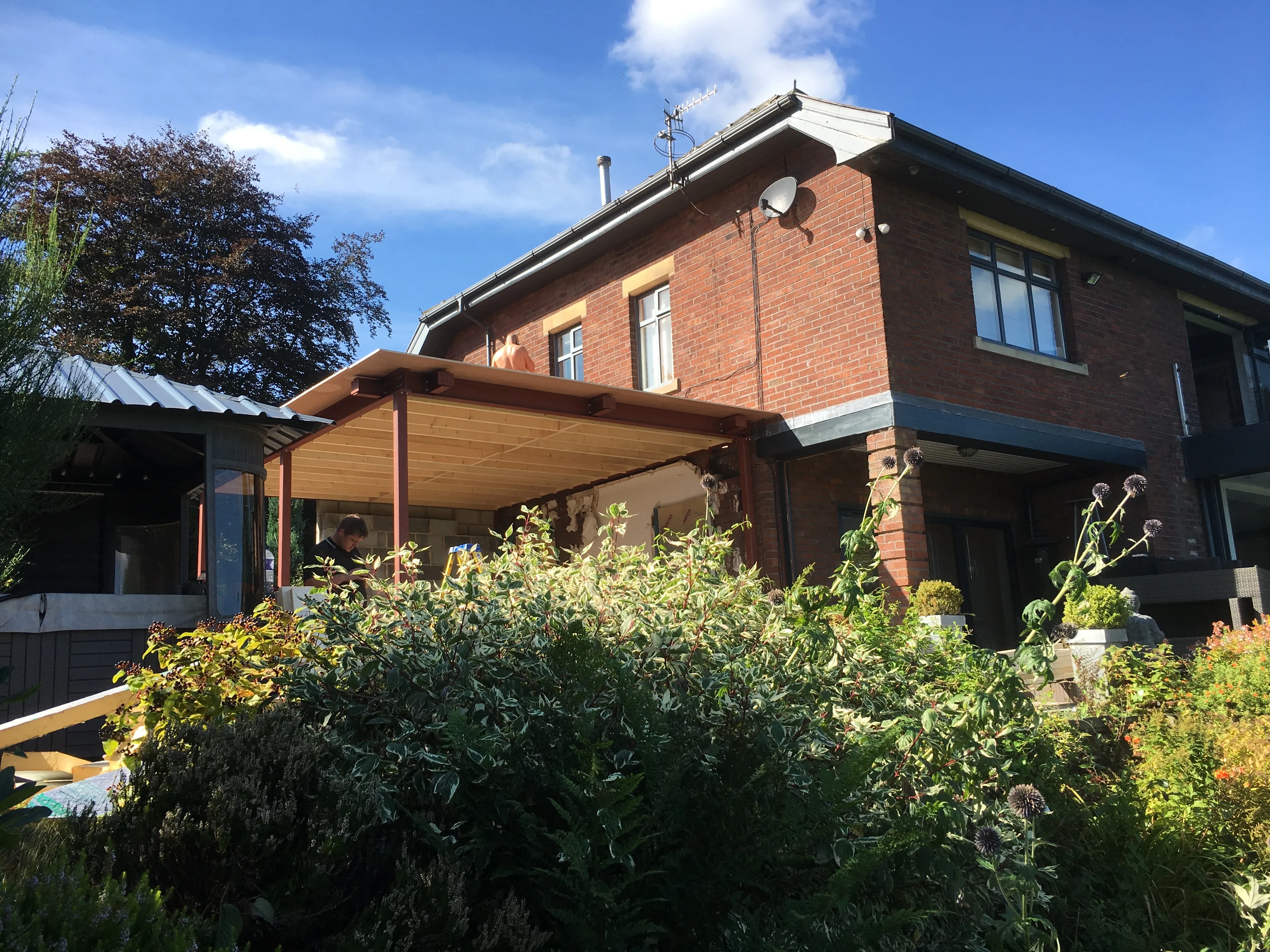 Detached brick house with a timber canopy and garden