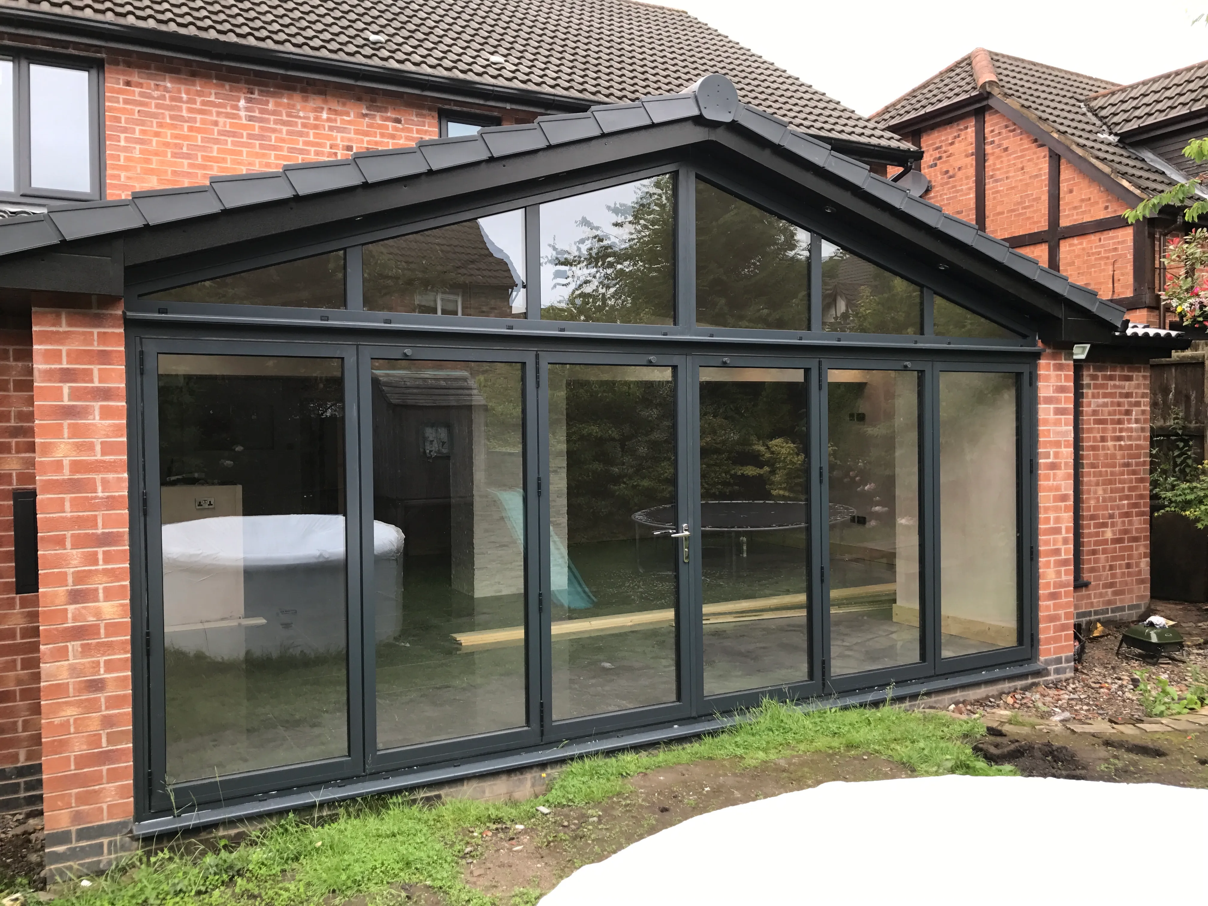 Pitched-roof glazed extension with bifold doors on a brick house
