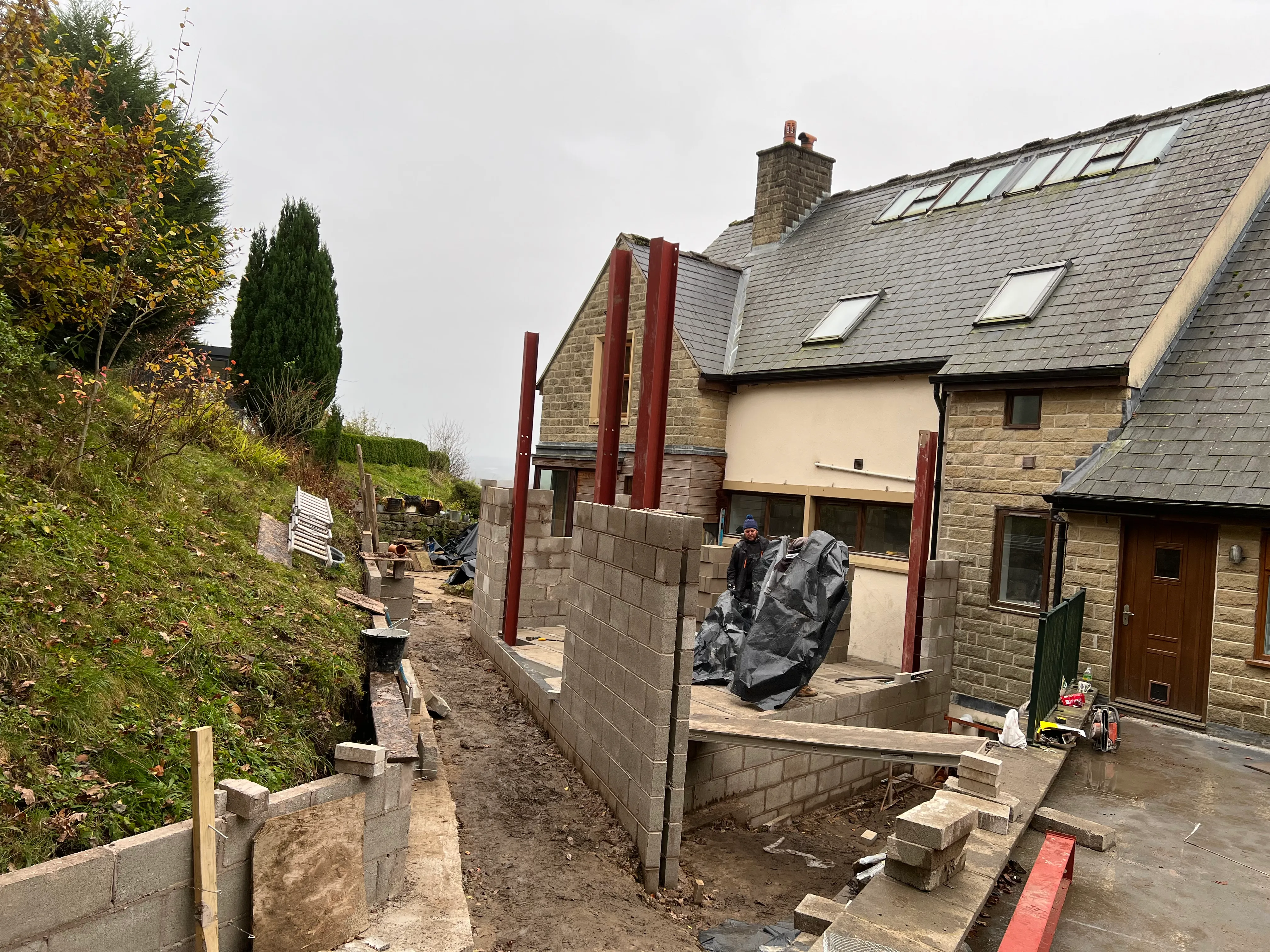 Structural steel frame: Steel columns and blockwork rising beside the existing house.