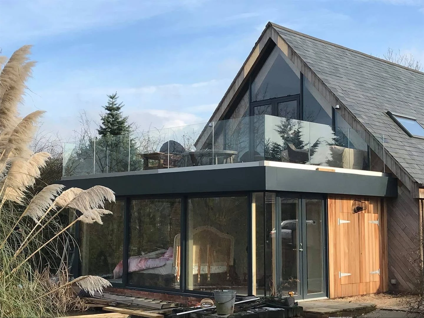 Gable-end extension with full-height glazing, timber cladding and a glass-balustrade balcony