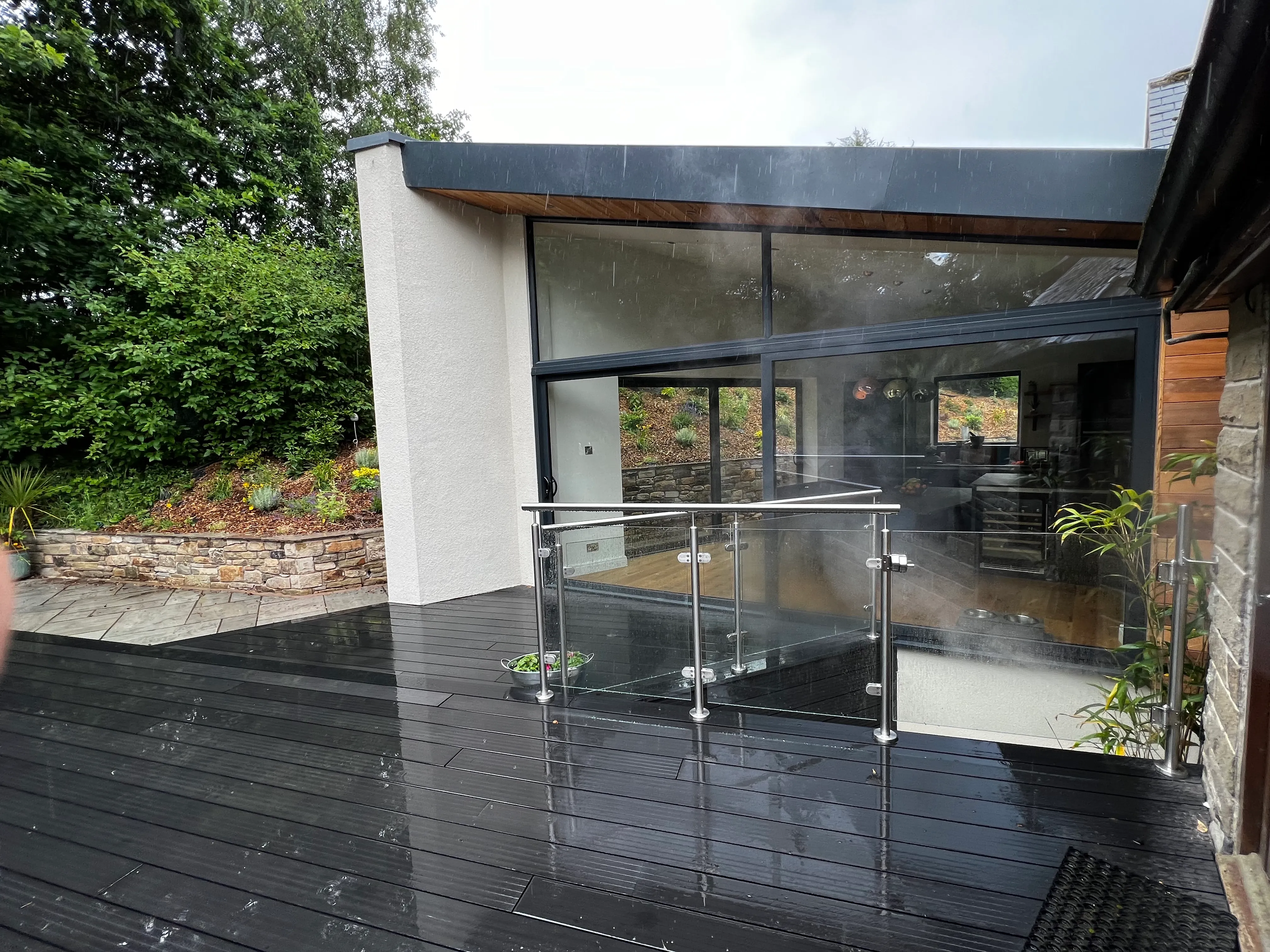 Glazed extension and deck: Anthracite glazing, cedar and render with a composite deck.